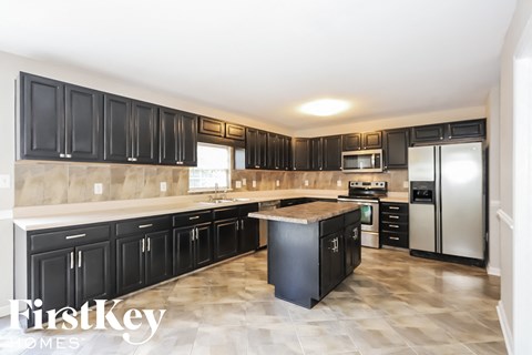 A kitchen with black cabinets and a tiled floor.