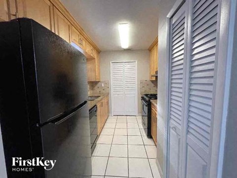 a kitchen with a black refrigerator and a white floor