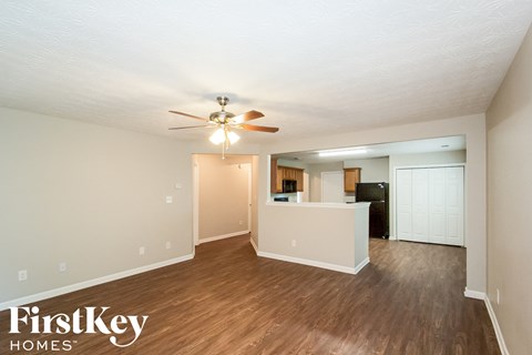 A spacious room with a ceiling fan and wooden flooring.