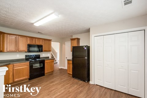A kitchen with wooden cabinets and a black refrigerator.