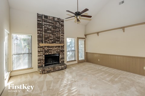A living room with a fireplace and a fan.