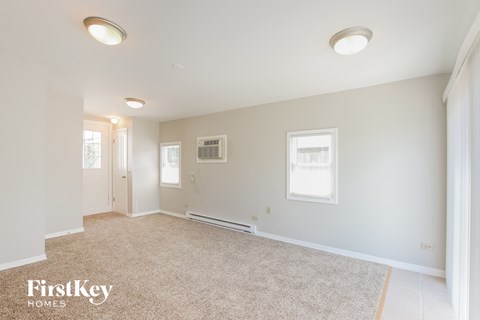 a spacious living room with carpet and white walls