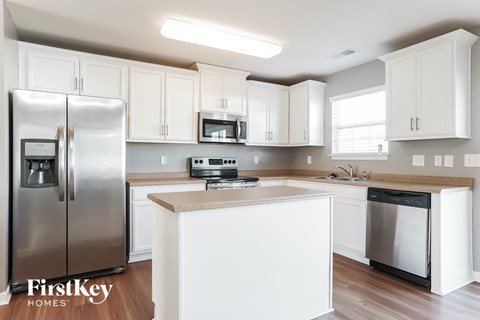 A kitchen with white cabinets and a stainless steel refrigerator.