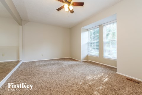 a spacious living room with carpet and a ceiling fan