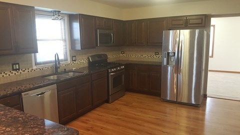 A kitchen with wooden cabinets and a stainless steel refrigerator.