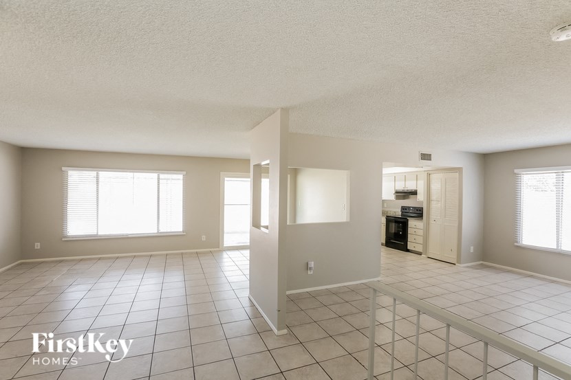 an empty living room and kitchen with tiled flooring