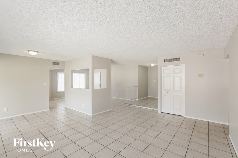 an empty living room with a tile floor and white walls