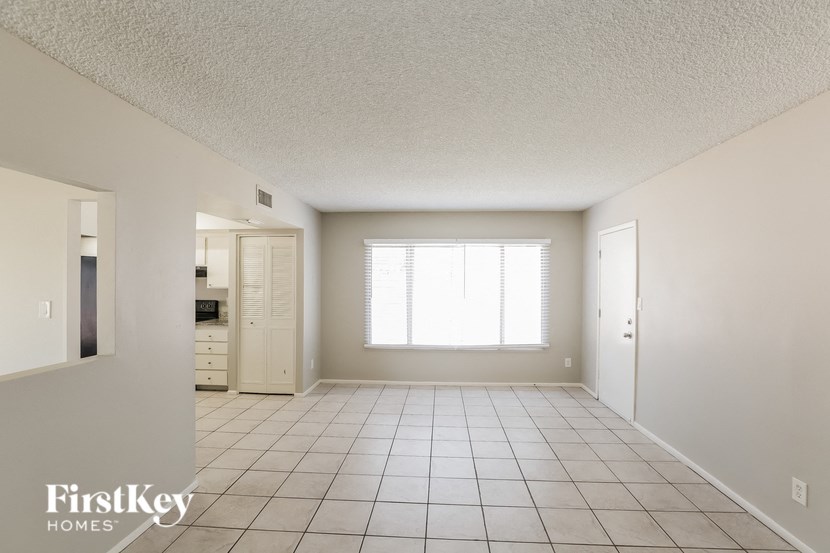 an empty living room with a white tile floor and a window