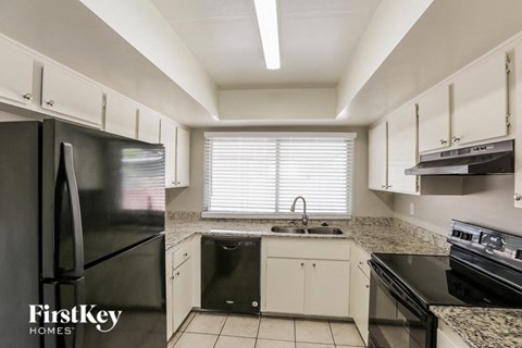 a kitchen with white cabinets and black appliances