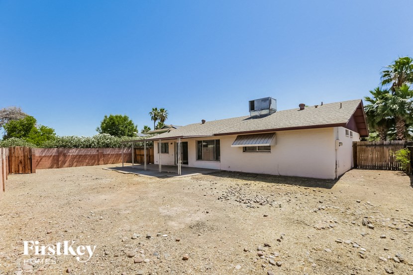 a small house with a dirt lot and a fence