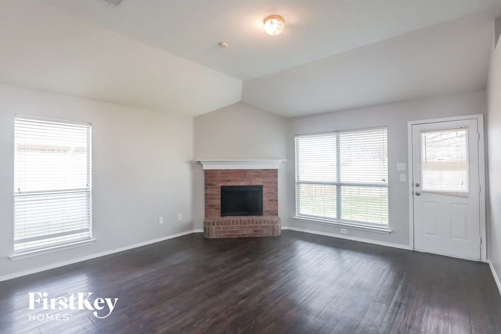 A large empty room with a fireplace and a television.