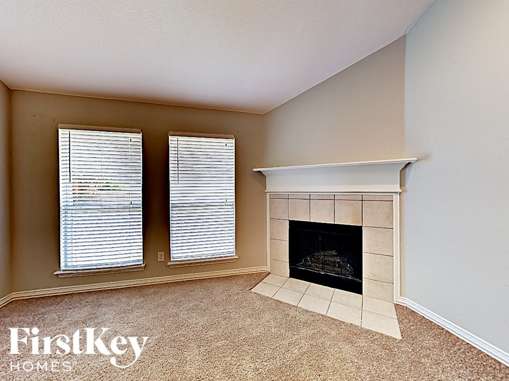 A room with a fireplace and two windows.