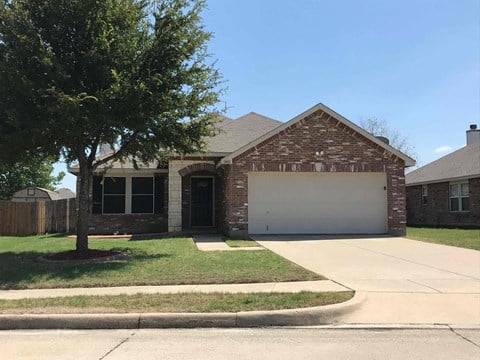 A house with a garage and a tree in front.