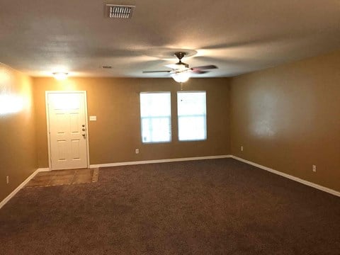 A room with brown carpeting and a ceiling fan.