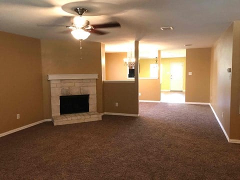 A living room with a fireplace and a ceiling fan.