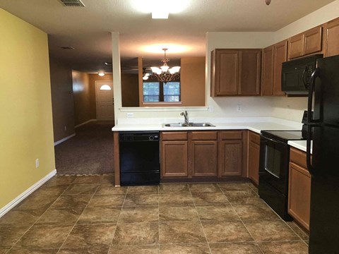 A kitchen with brown cabinets and black appliances.
