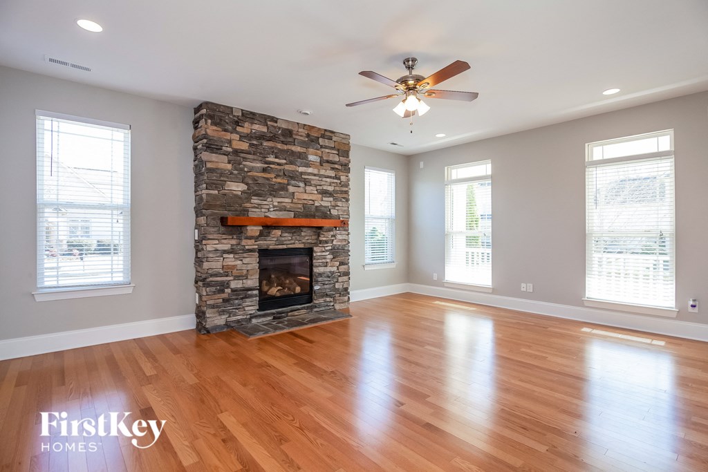 A spacious room with a stone fireplace and wooden floors.