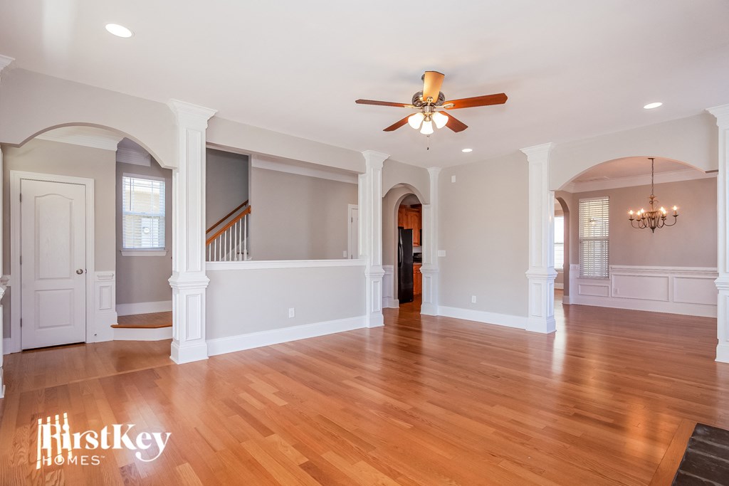 A spacious room with a ceiling fan and wooden flooring.