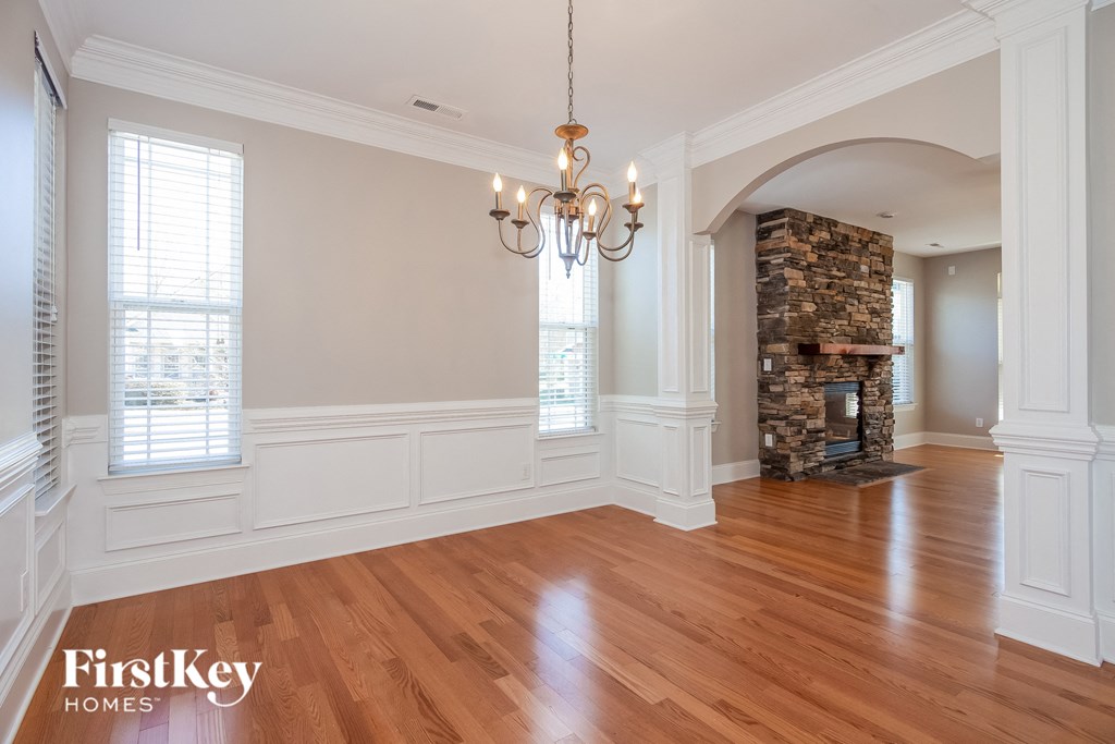 A large, empty room with wooden floors and a stone fireplace.