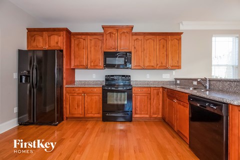 A kitchen with wooden cabinets and a black fridge.