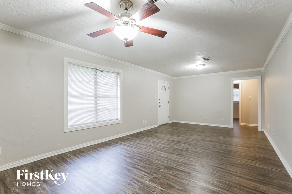 A room with a ceiling fan and wooden flooring.