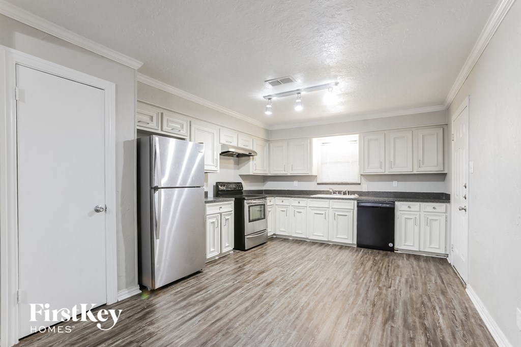 A kitchen with a refrigerator, microwave, and trash can.