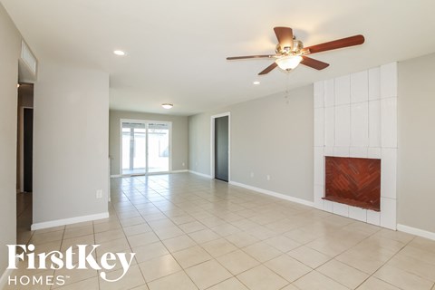 A spacious room with a ceiling fan and a fireplace.
