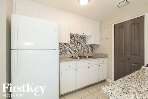 A kitchen with a white fridge and a granite counter top.