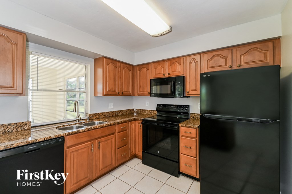 a kitchen with black appliances and granite counter tops and wooden cabinets