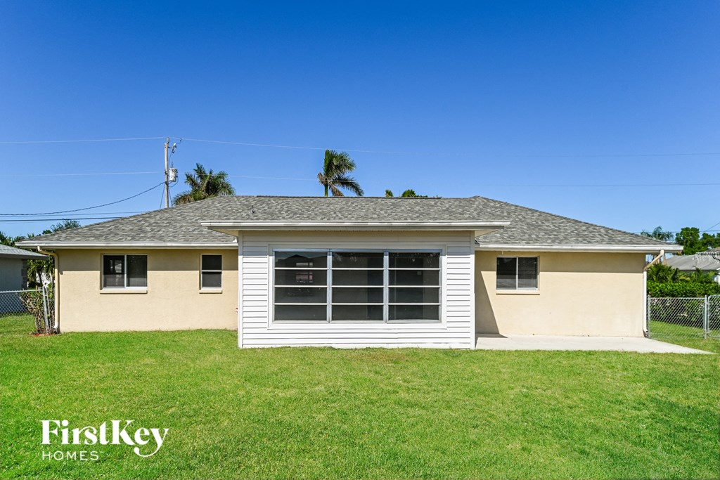 a small yellow house with a yard and a white fence
