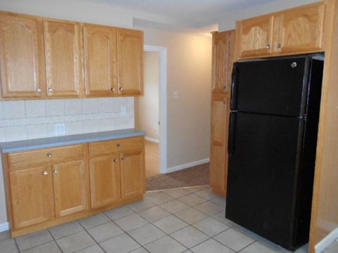 A kitchen with wooden cabinets and a black refrigerator.