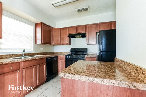 A kitchen with brown cabinets and a granite counter top.