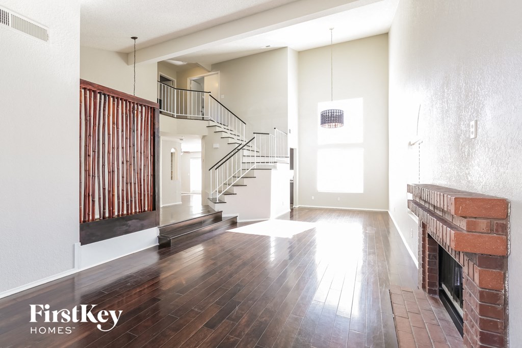 A spacious living room with a fireplace and a staircase.