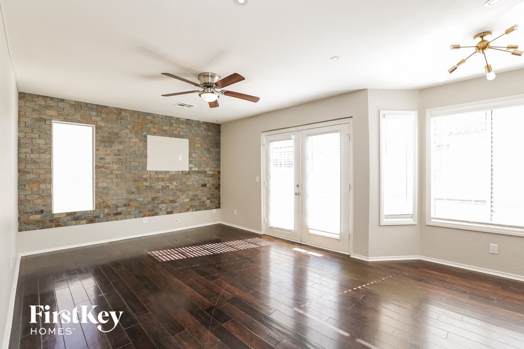 A spacious room with wooden floors and a brick wall.