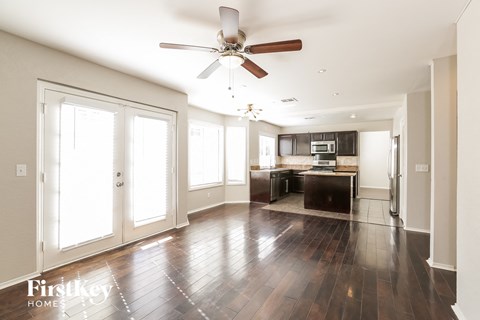 A spacious kitchen with dark wood floors and a ceiling fan.