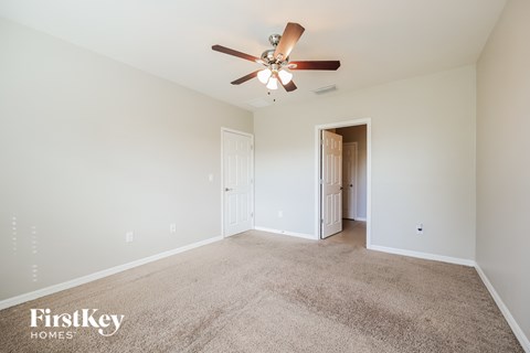 a spacious living room with carpet and a ceiling fan