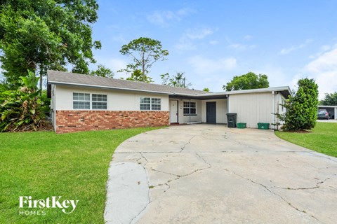a white and brick house with a driveway and grass