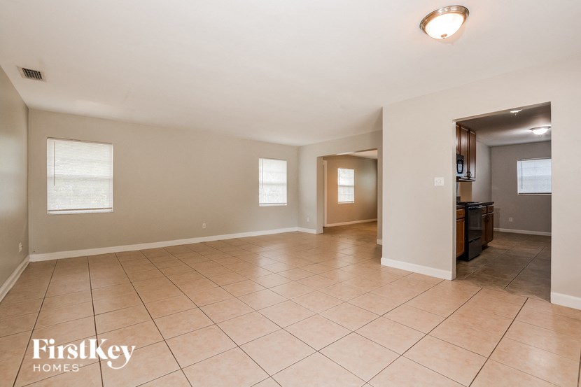 a spacious living room and kitchen with tiled flooring
