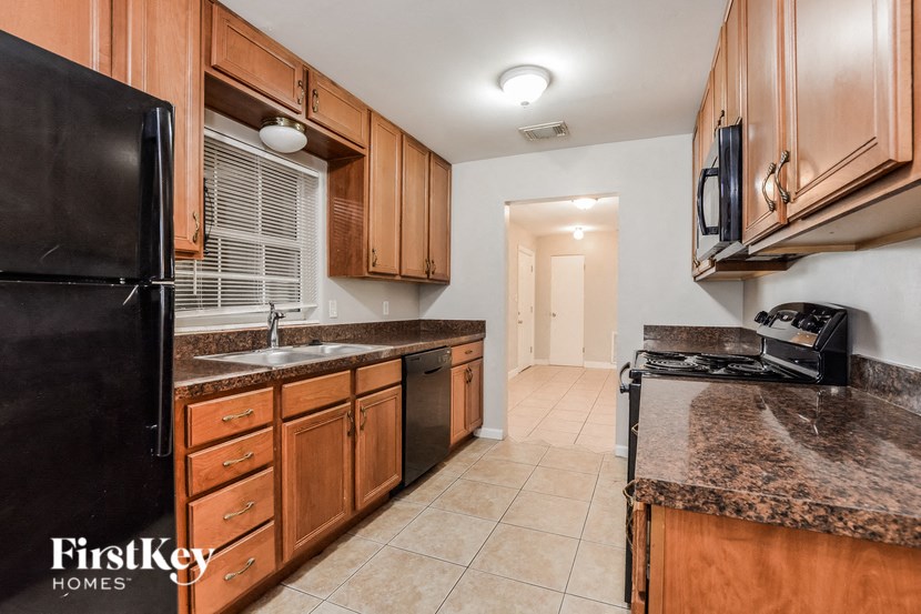 a kitchen with wood cabinets and black appliances and granite counter tops