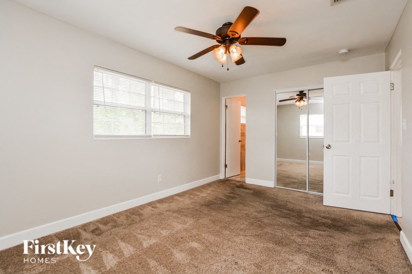 an empty living room with a ceiling fan and a closet