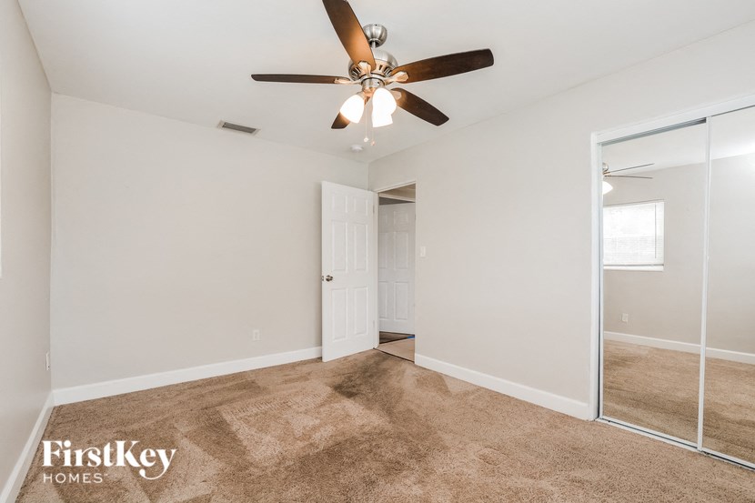 an empty living room with a ceiling fan and a mirror