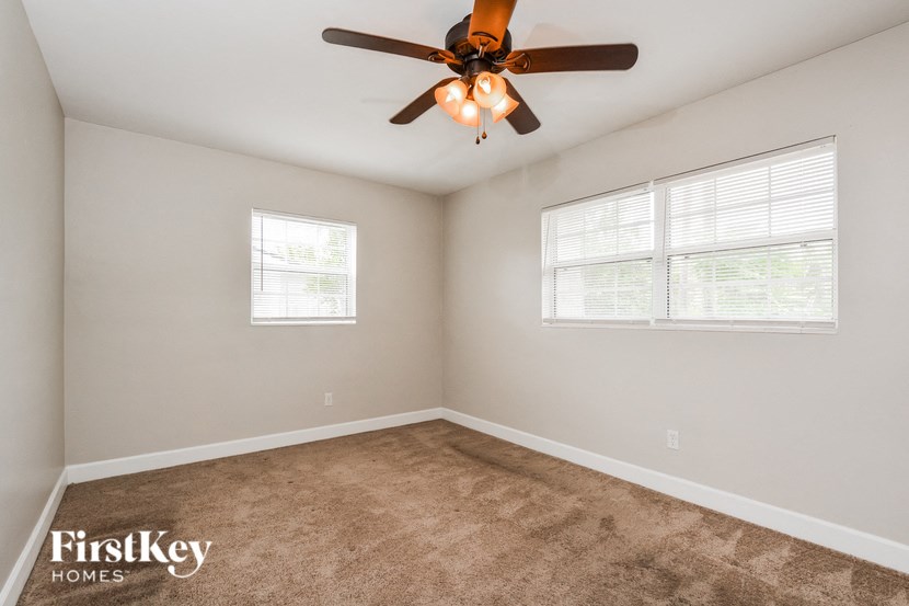 a bedroom with a ceiling fan and two windows