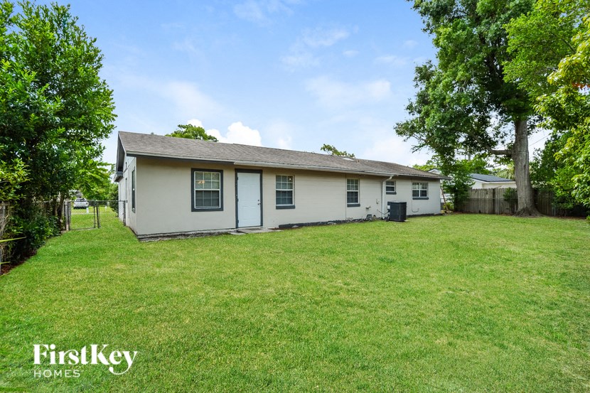 a white house with a grassy yard and some trees