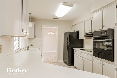 A kitchen with white cabinets and black appliances.