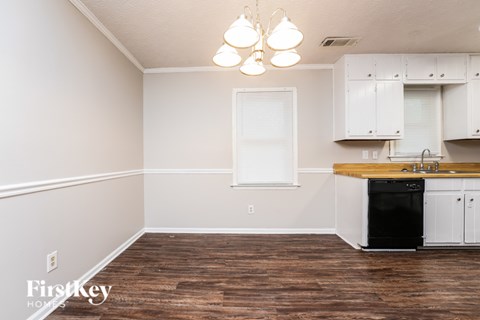 A kitchen with a black dishwasher and white cabinets.