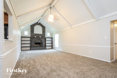 A spacious room with a fireplace and a carpeted floor.