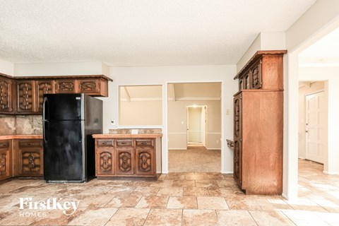 A kitchen with a black fridge and wooden cabinets.