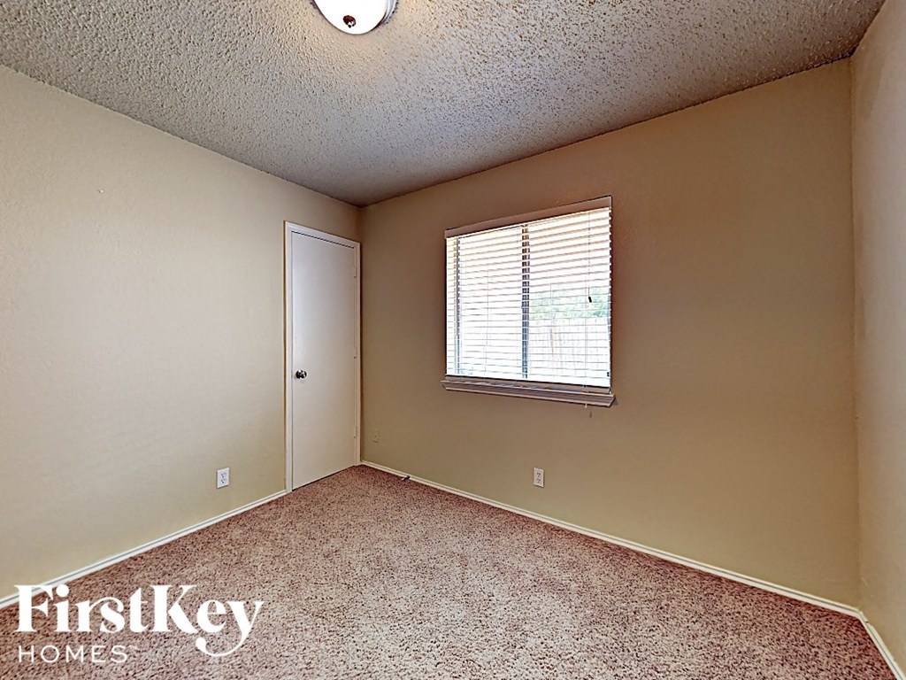 A room with a carpeted floor and a window with blinds.