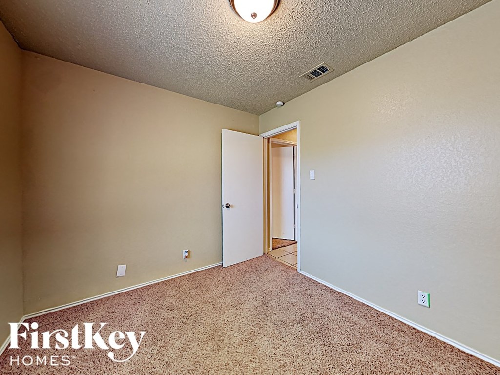 A room with a carpeted floor and a doorway leading to another room.