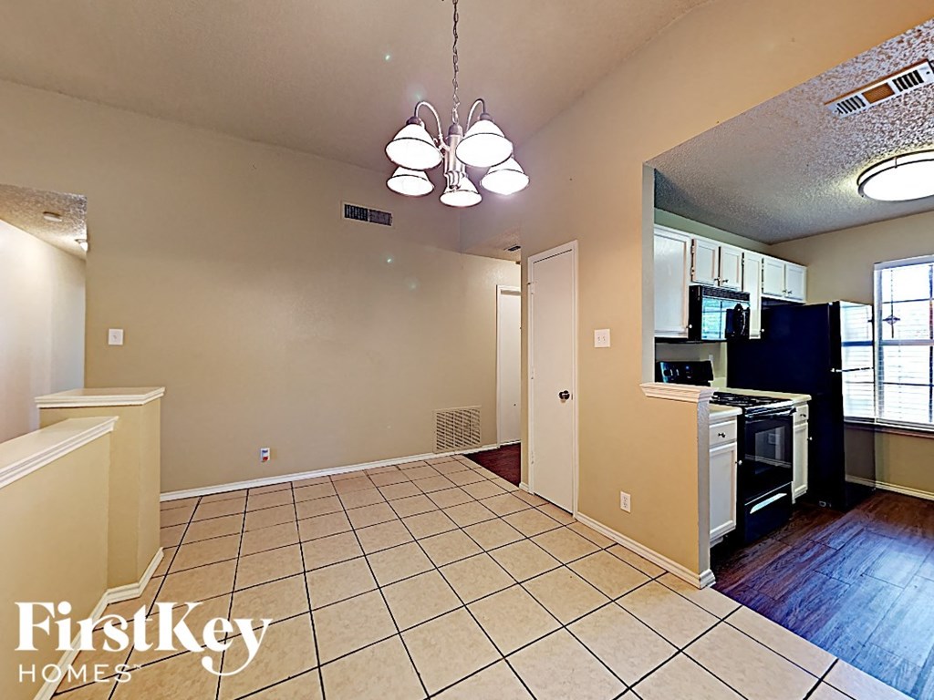 A kitchen area with a tile floor and a stove top oven.